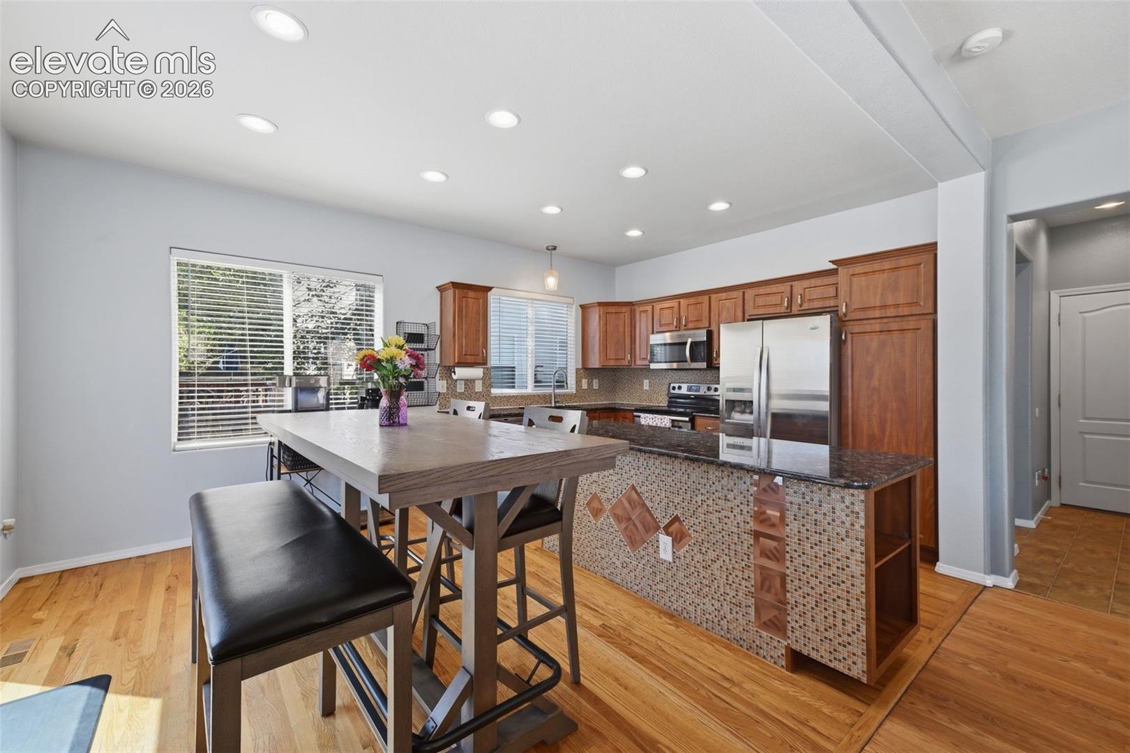 Kitchen featuring wood-finish flooring, recessed lighting, and a kitchen island with stone countertops