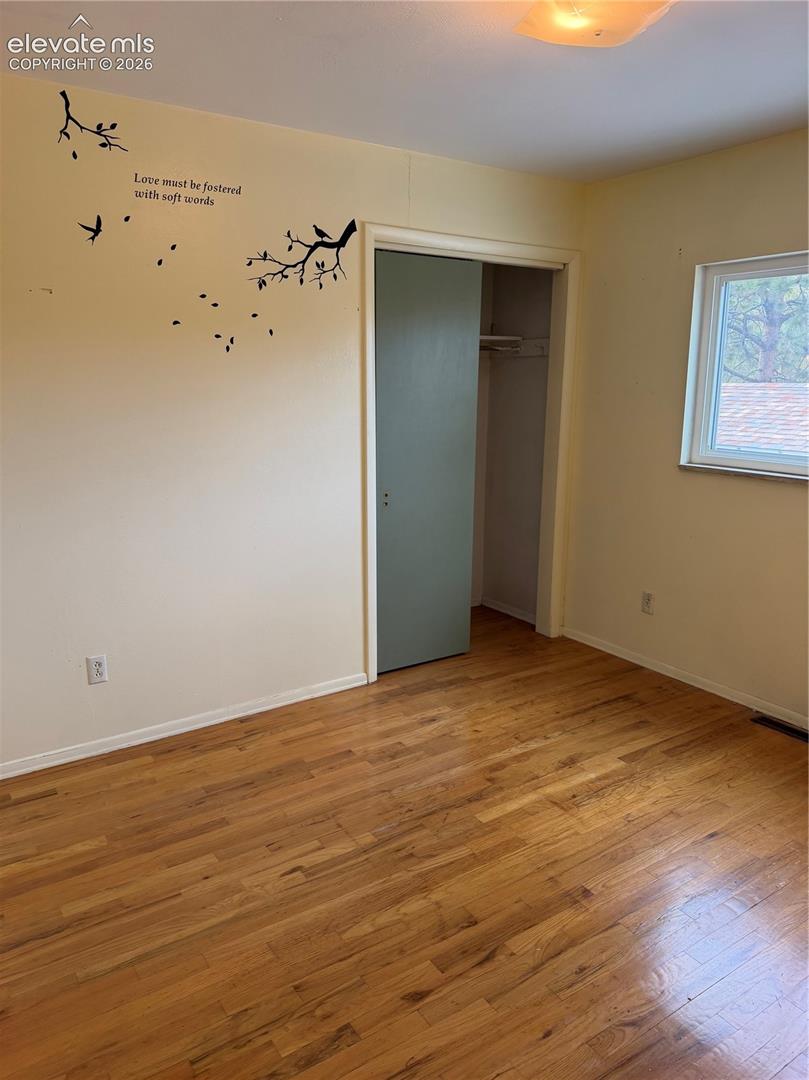 Room featuring wood-finish flooring, a single window, and a built-in closet with a swing door