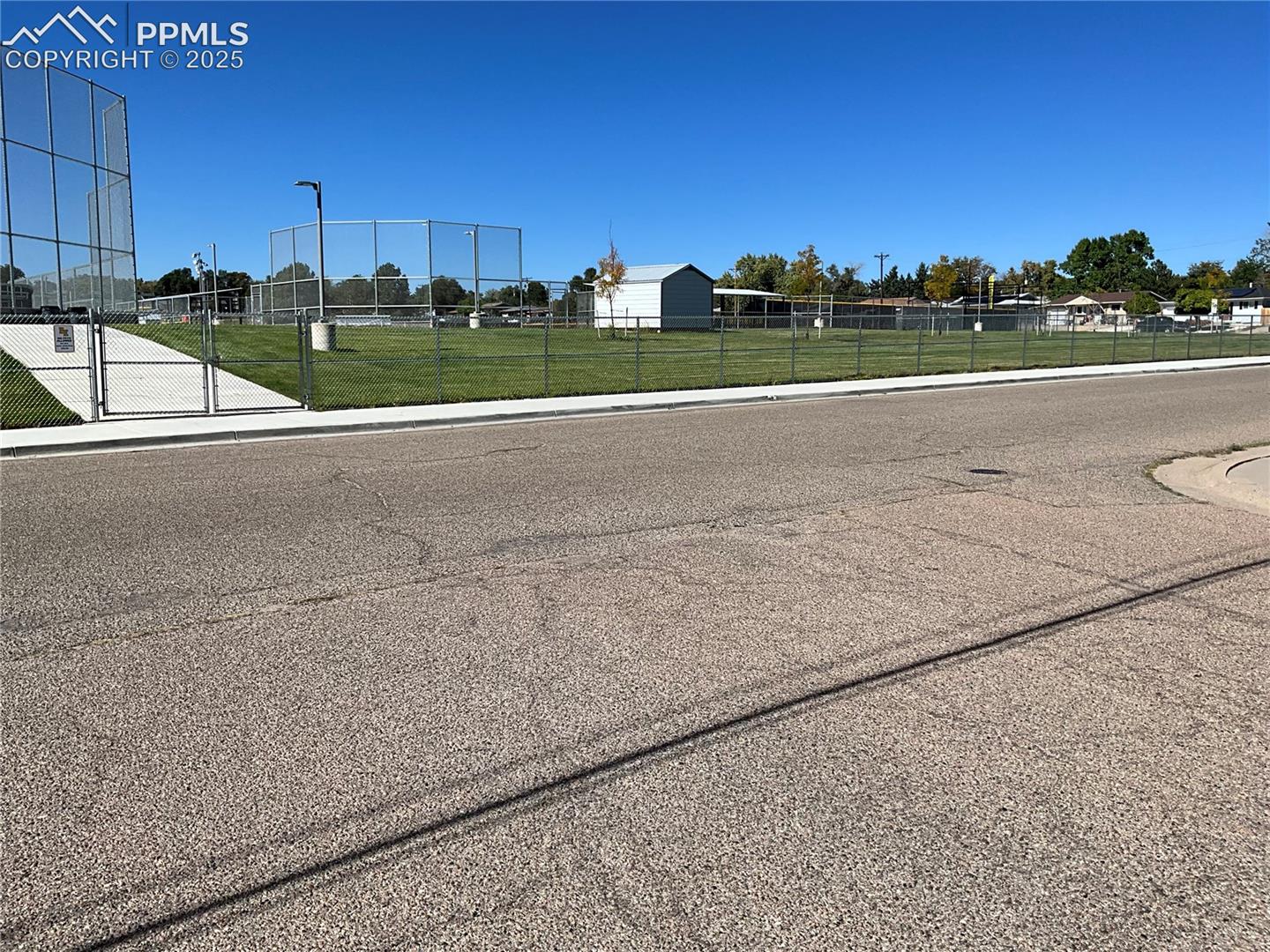 View of asphalt road featuring sidewalks and curbs