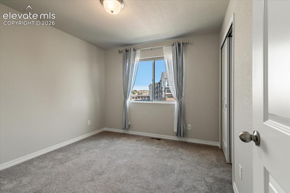 Neutral-toned walls with carpeted flooring, a window with a white frame, and a flush-mount ceiling light fixture