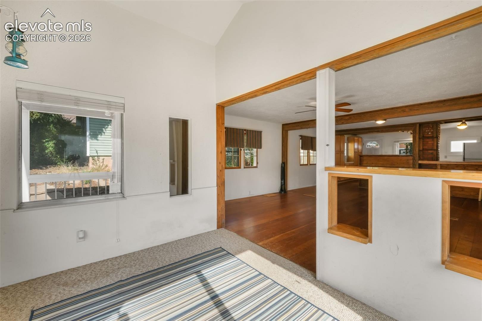 Vaulted ceiling, wood-finish flooring, wood trim details, recessed lighting, and a built-in shelf