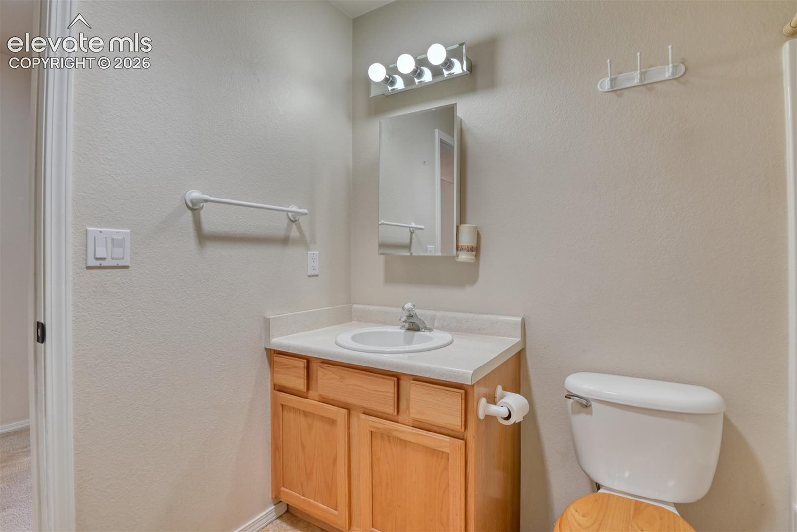 Bathroom featuring a wood-finish vanity with a molded countertop, integrated sink, mirrored medicine cabinet, and four-bulb light fixture