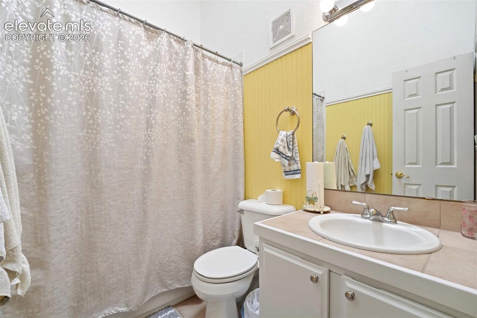 Bathroom with a single vanity, a large mirror, and a shower with a curtain