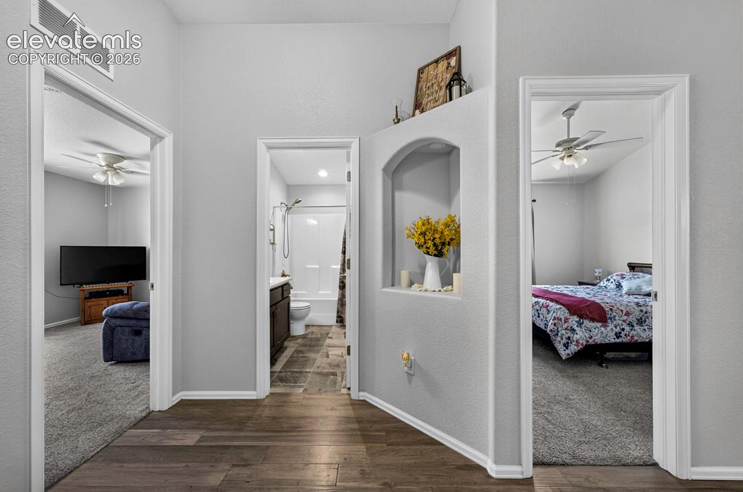 Hallway featuring wood-finish flooring, a decorative wall niche, and an arched wall cutout