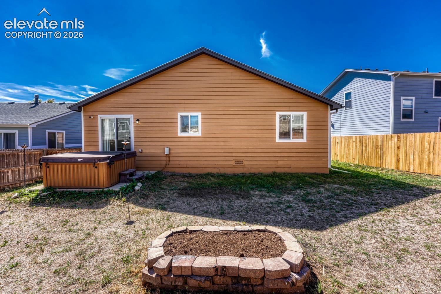 Rear view of home and backyard with raised flower bed, concrete patio.  Hot tub is no longer there.