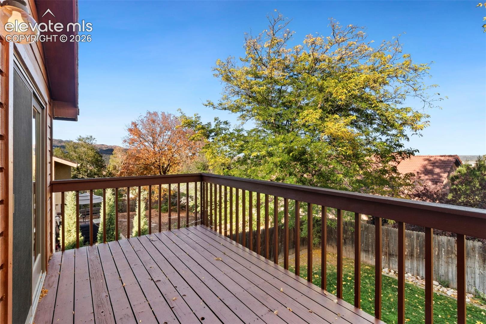 Elevated wood deck featuring a painted wood railing and wall-mounted exterior light fixture