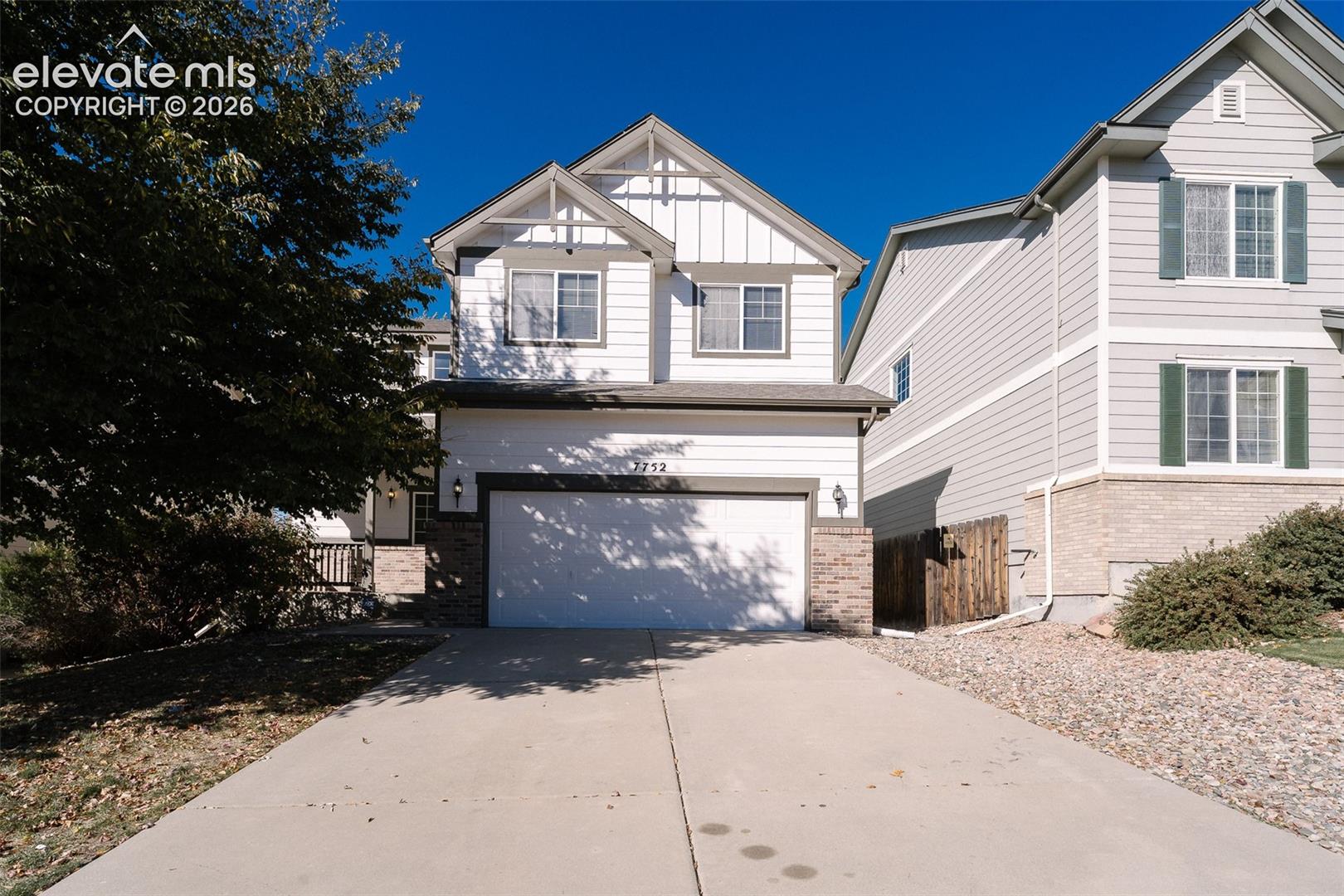 Two-story residence featuring horizontal lap siding, vertical board-and-batten gable accents, stone masonry foundation detailing, and an attached two-car garage