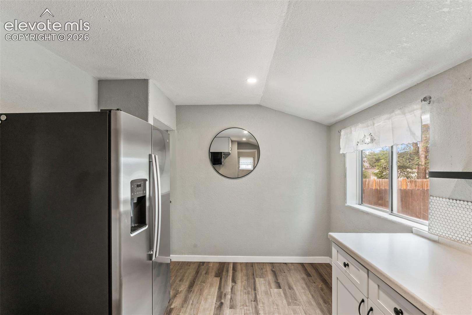 Contemporary kitchen featuring wood-finish flooring, white cabinetry with dark hardware, a white countertop, and a white penny-round tile backsplash