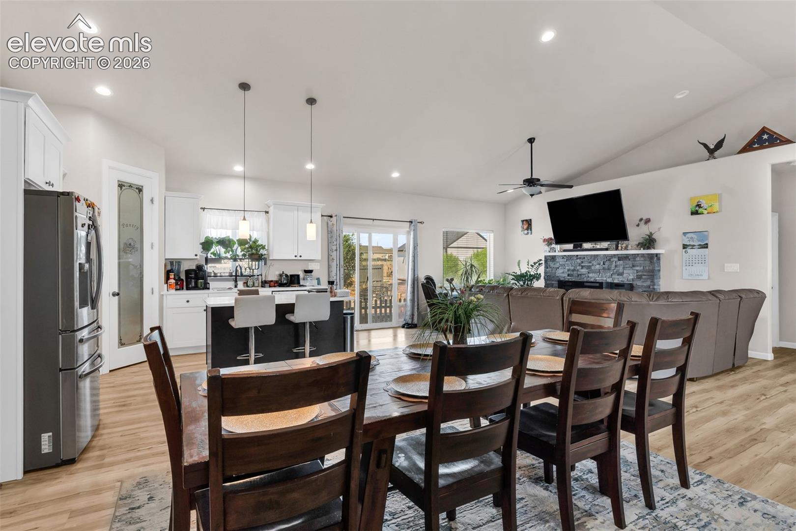 Open-concept interior featuring wood-finish flooring, recessed lighting, and a vaulted ceiling