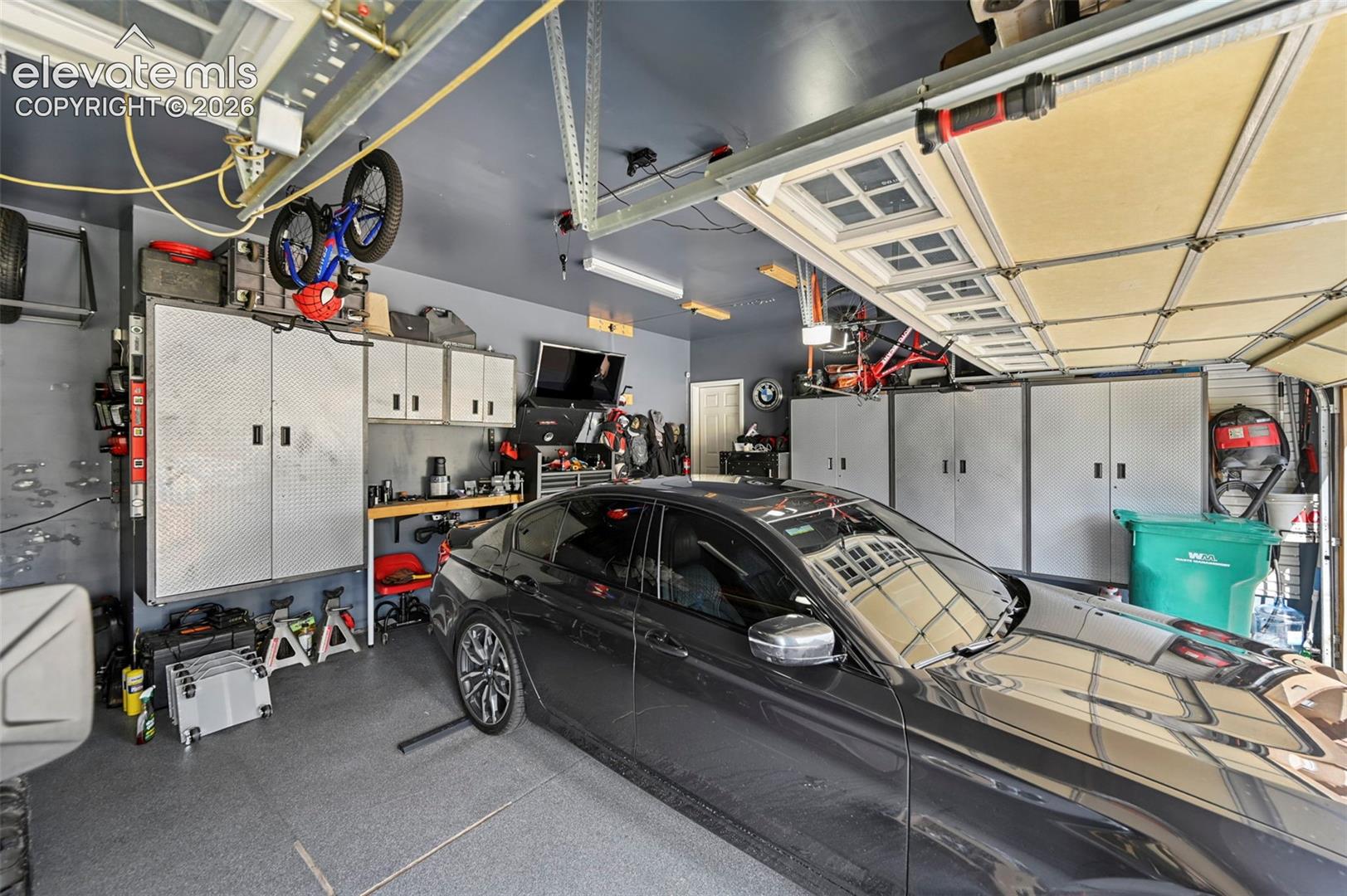Garage featuring integrated overhead storage, multiple built-in metal storage cabinets, and a textured floor finish