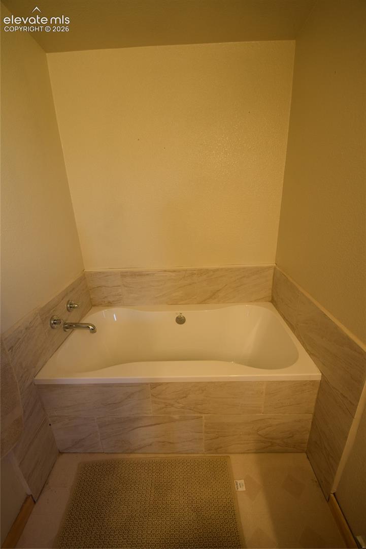 Built-in soaking tub with chrome fixtures, surrounded by light-toned tile
