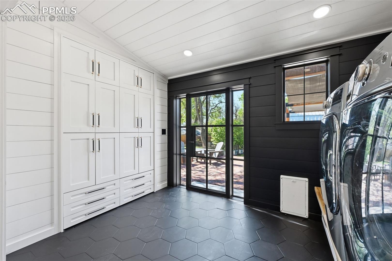 The laundry space is complete with a stunning metal rear door, convenient dog door, and tons of storage provided by built-in storage cabinets.