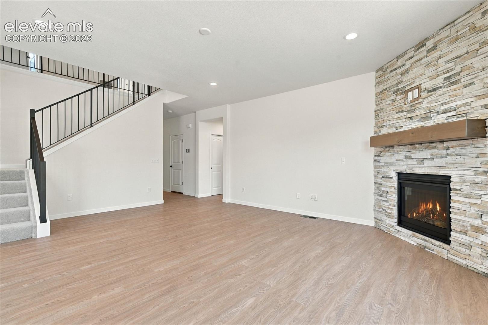The Great Room features a Gas fireplace with stone extended to the ceiling, wood mantle, LVP Flooring, and recessed lighting.