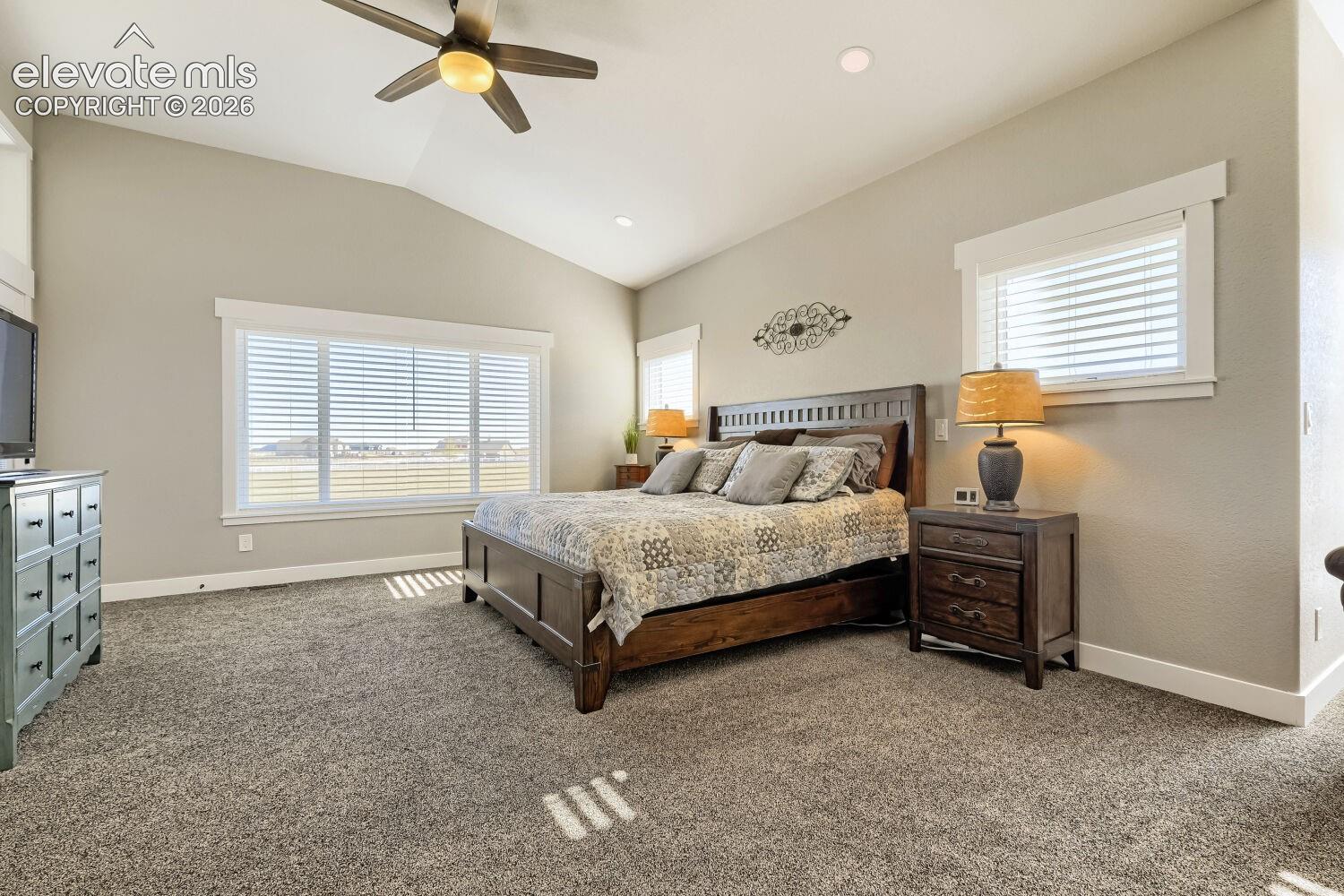 Vaulted ceilings with a ceiling fan and recessed lighting, large windows with white blinds, and carpeted flooring