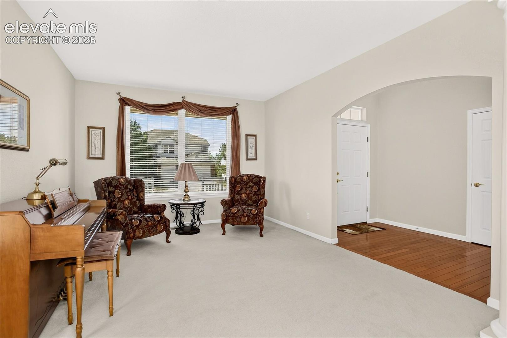 Arched entryway leading to a foyer with wood-finish flooring
