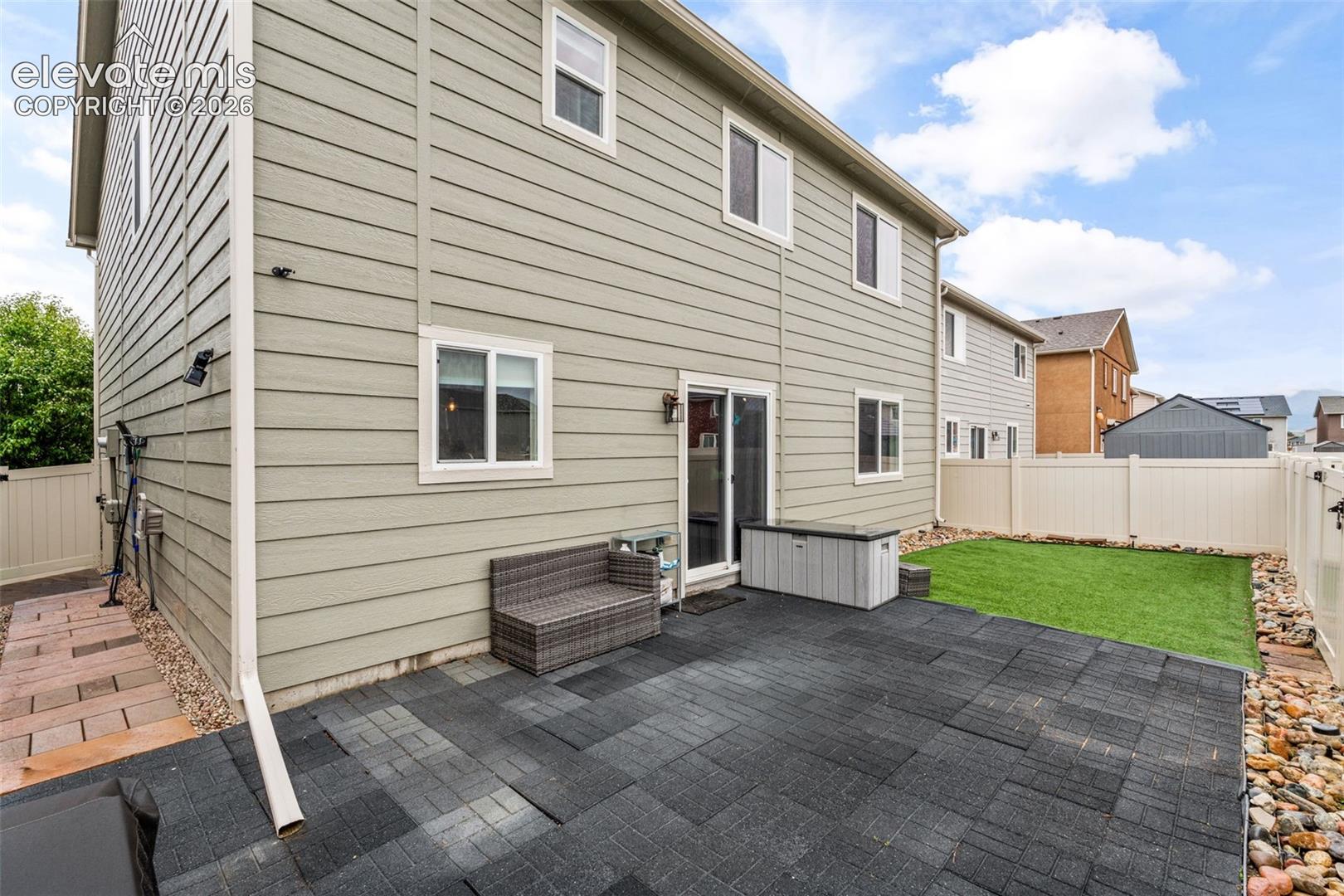 Ground-level patio with dark pavers, complemented by an artificial turf area