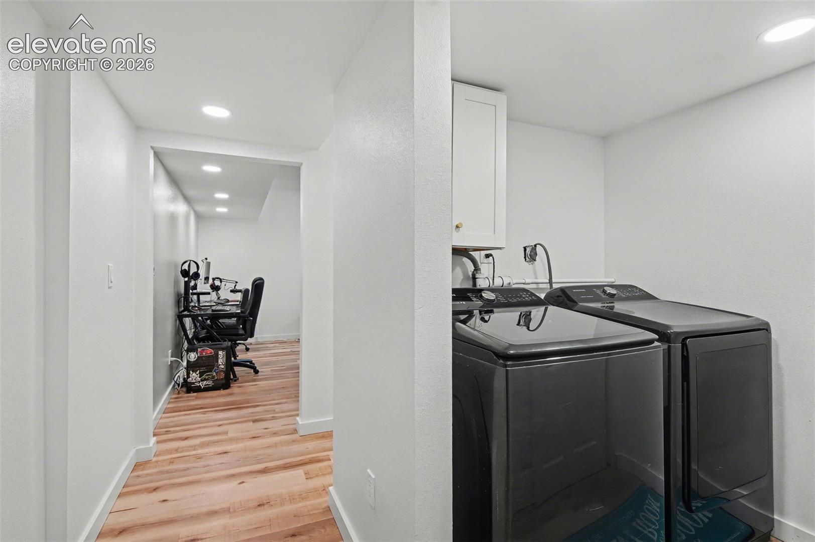 Laundry area featuring wood-finish flooring, recessed lighting, and wall-mounted cabinetry
