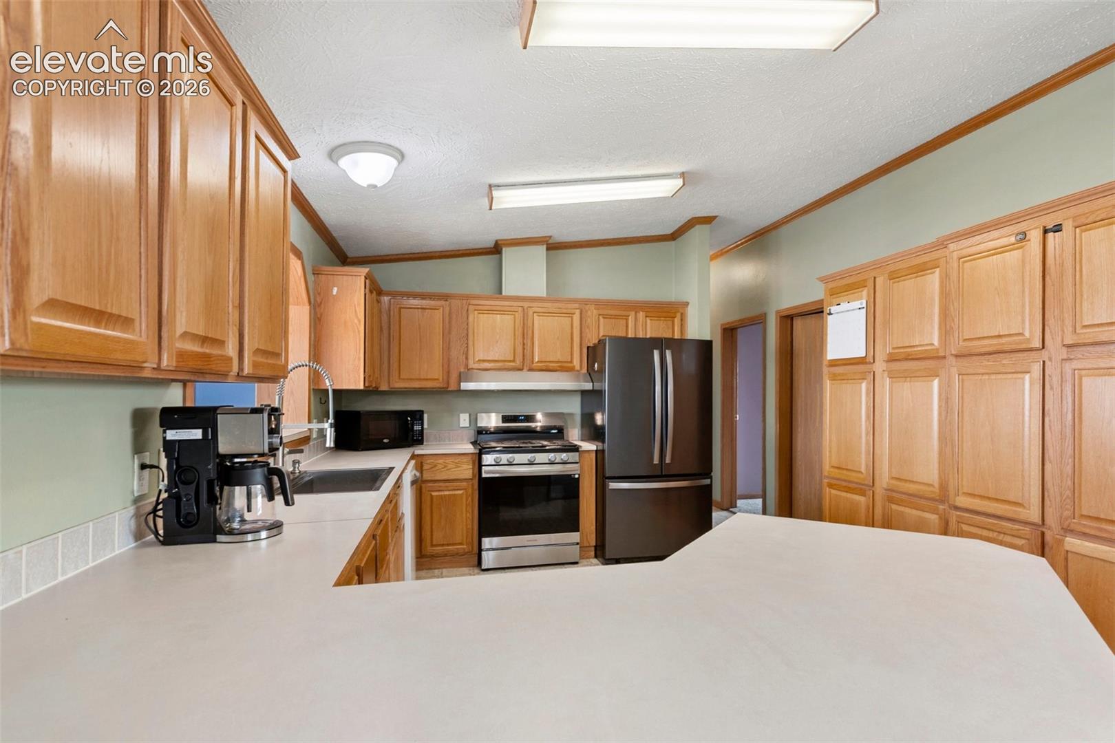 Kitchen featuring extensive wood cabinetry, light-toned countertops, and a full suite of stainless steel and black appliances