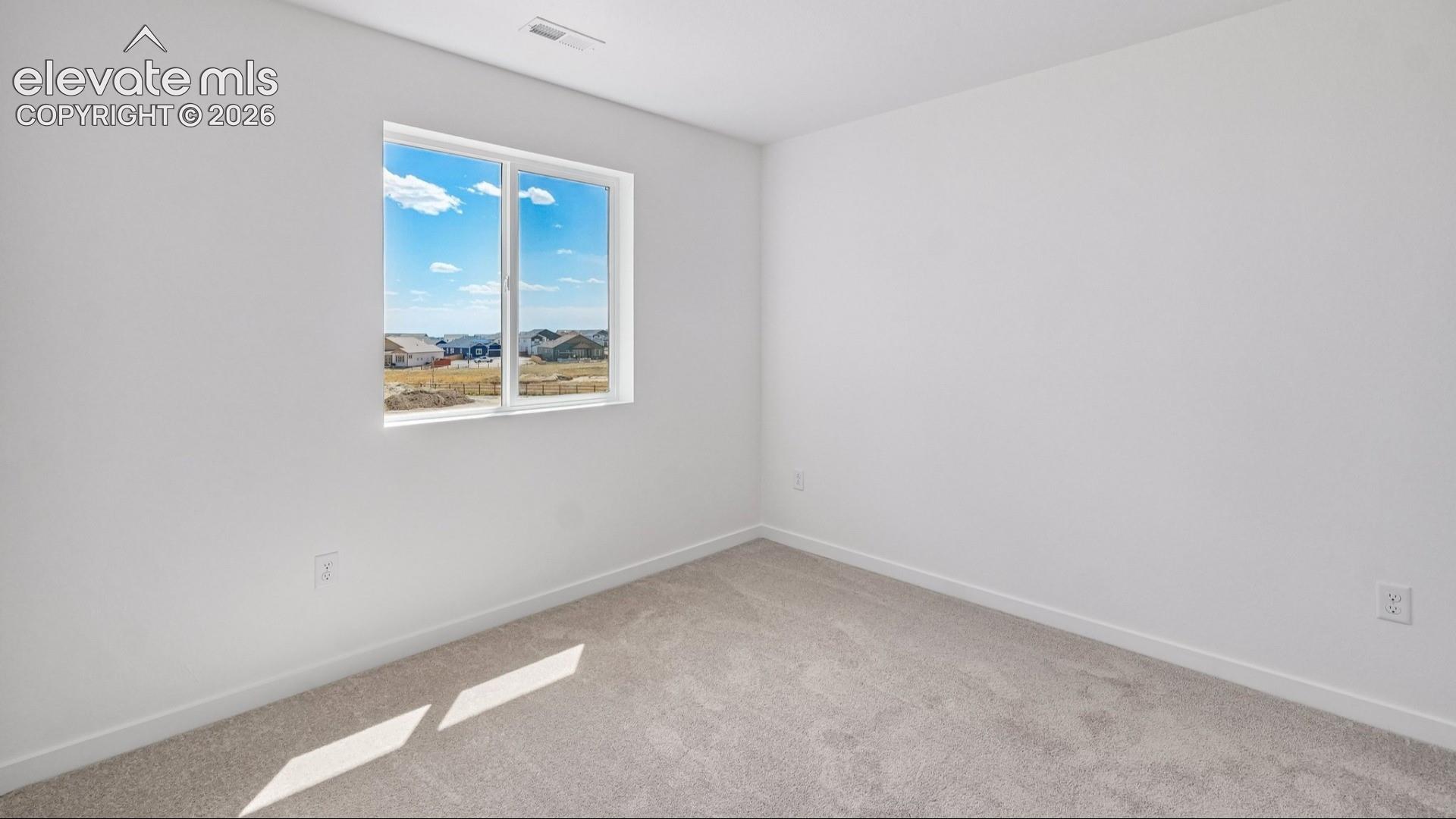 Neutral interior room featuring neutral-tone carpeting, white walls, and a large single-pane window with exterior surroundings