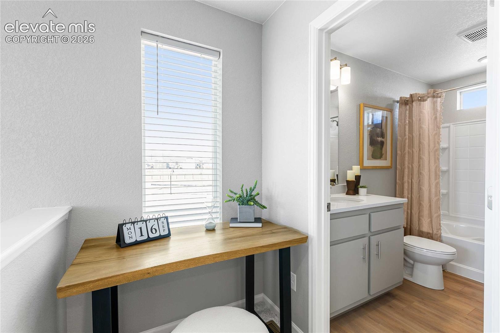 Compact desk area with a wood-finish surface and a window featuring horizontal blinds
*photos of a model home*