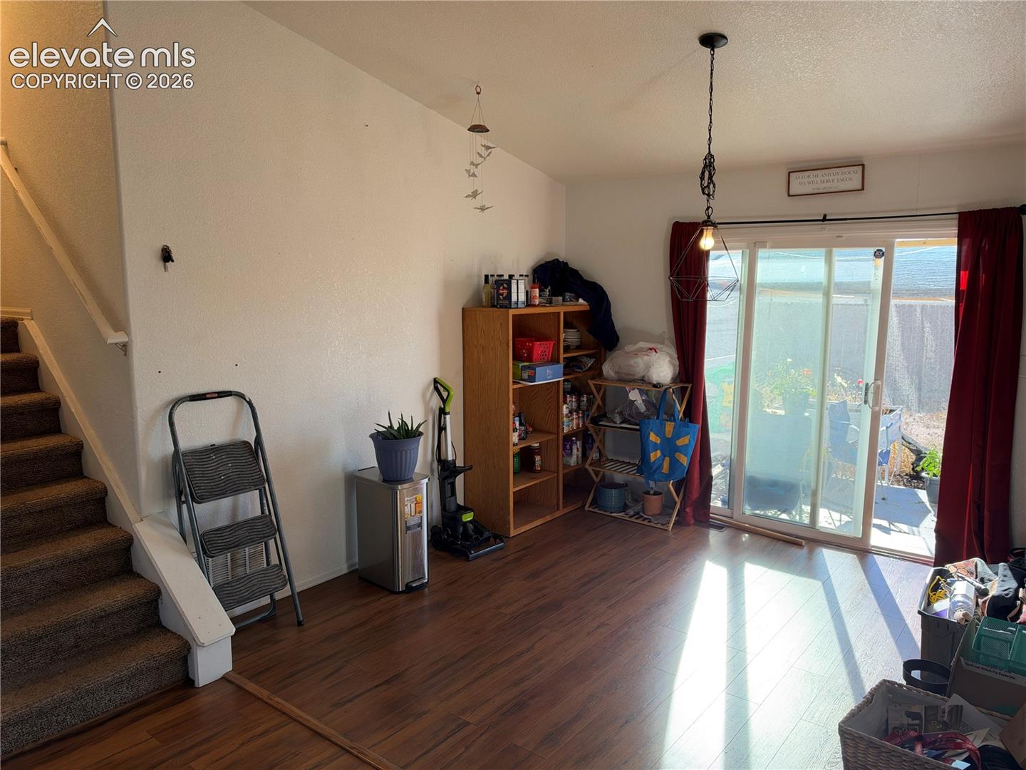 Interior featuring wood-finish flooring, sliding glass patio doors, and a suspended geometric pendant light fixture