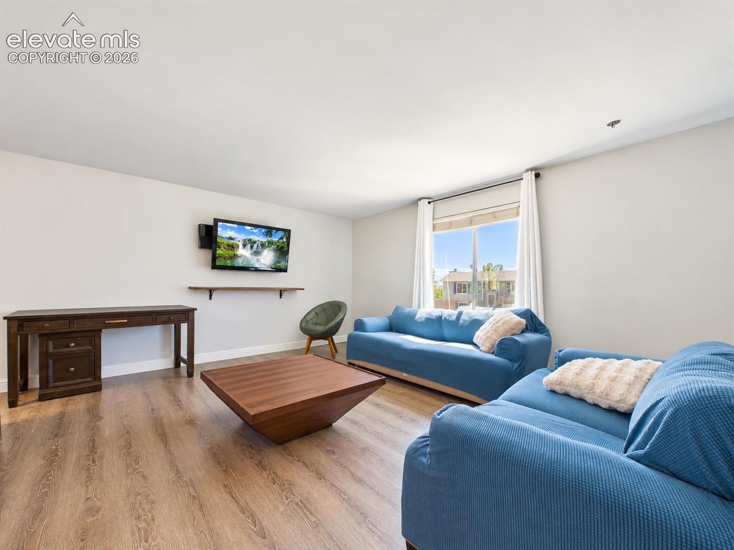 Bright living room with updated flooring, neutral finishes, and a large vinyl window providing abundant natural light.