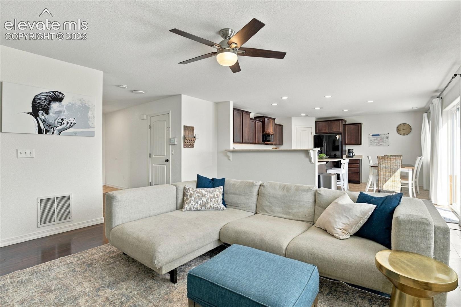 Open-concept living area featuring a ceiling fan with integrated lighting, recessed lighting, wood-finish flooring, and a sliding glass door