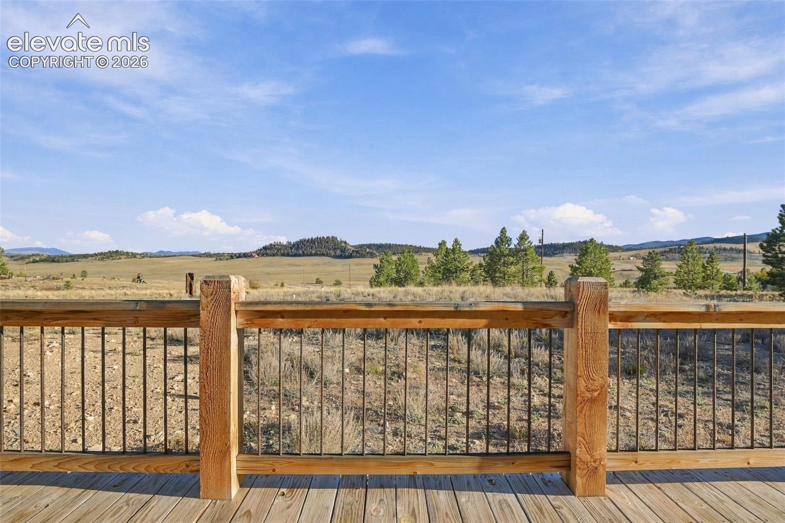 Outdoor deck featuring wood-plank flooring, substantial timber posts, and dark metal balusters