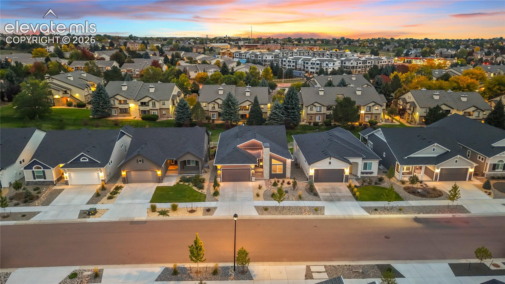 Aerial perspective of a suburban neighborhood featuring paved streets, concrete driveways, attached multi-car garages, multi-pitch roofs, and professional xeriscape landscaping