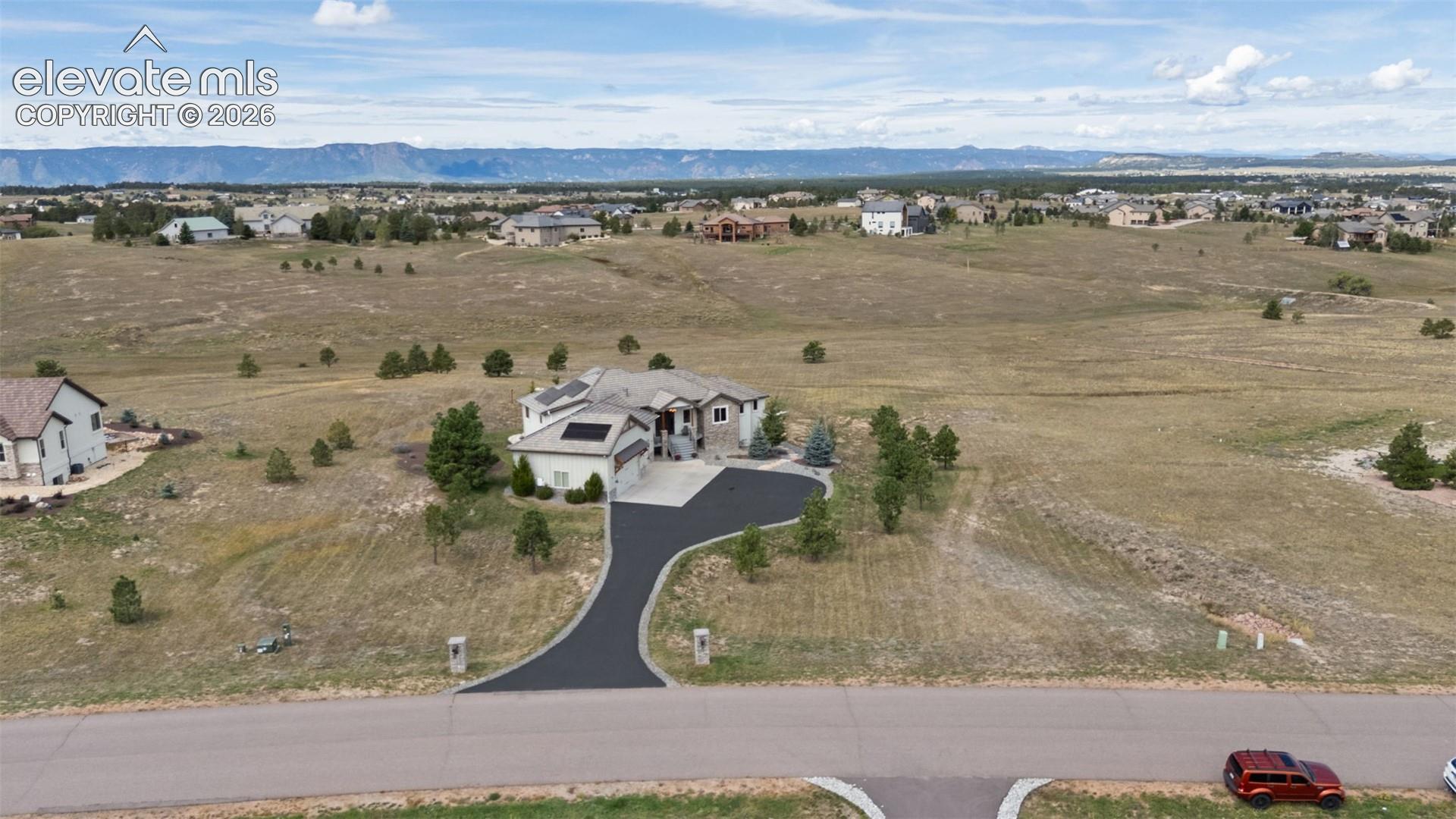 Expansive suburban property with a paved driveway, attached garage, and mountain backdrop