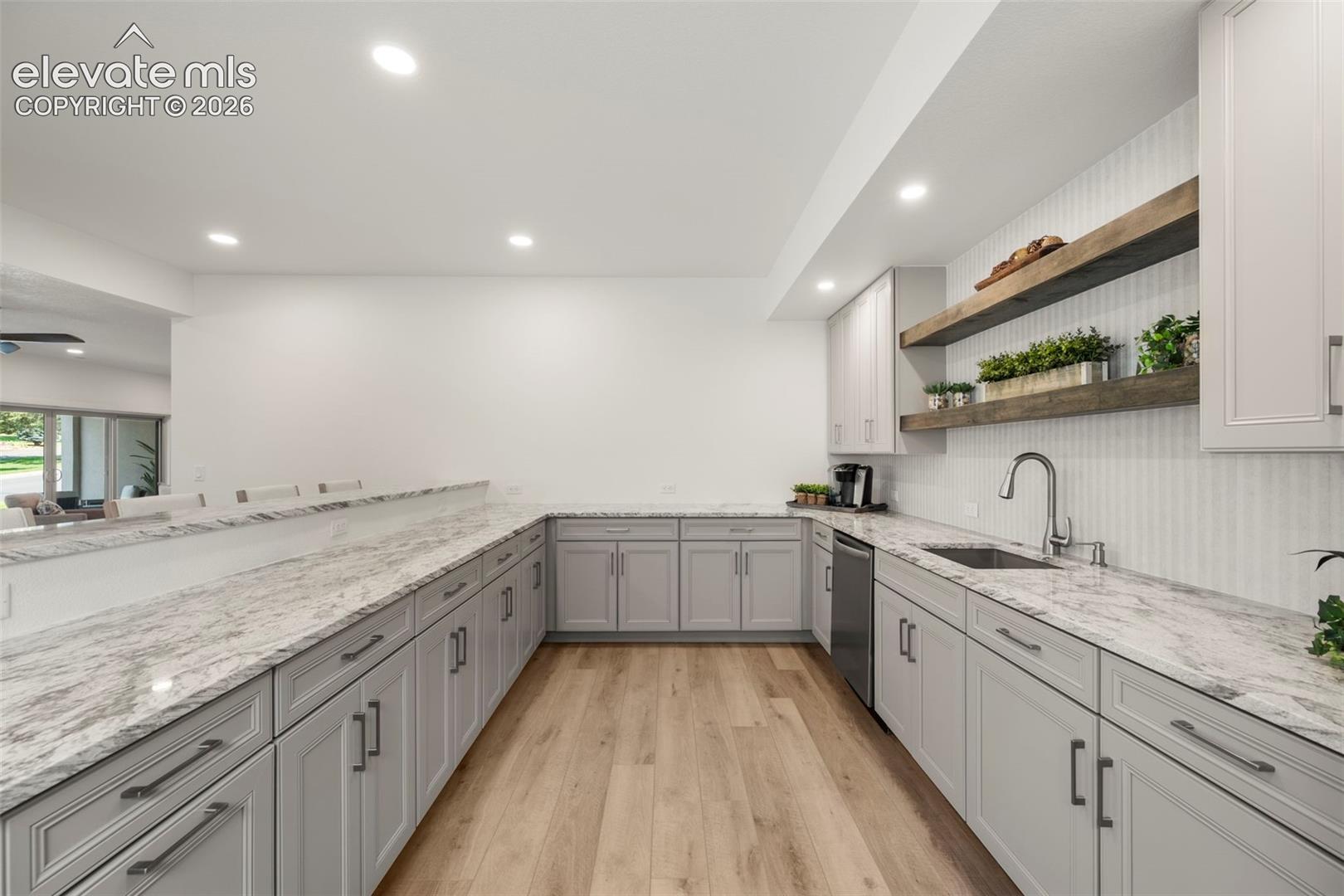 Extensive counter space with light-toned cabinetry, recessed lighting, wood-finish flooring, and open shelving
