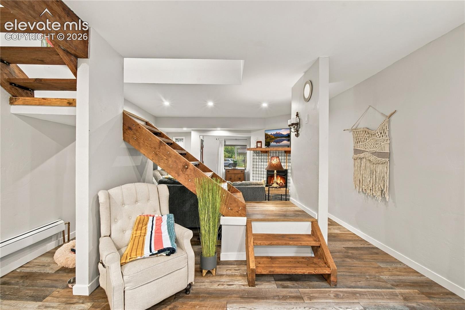 Wood-finish flooring, staircase with natural wood treads, and tile-surround fireplace