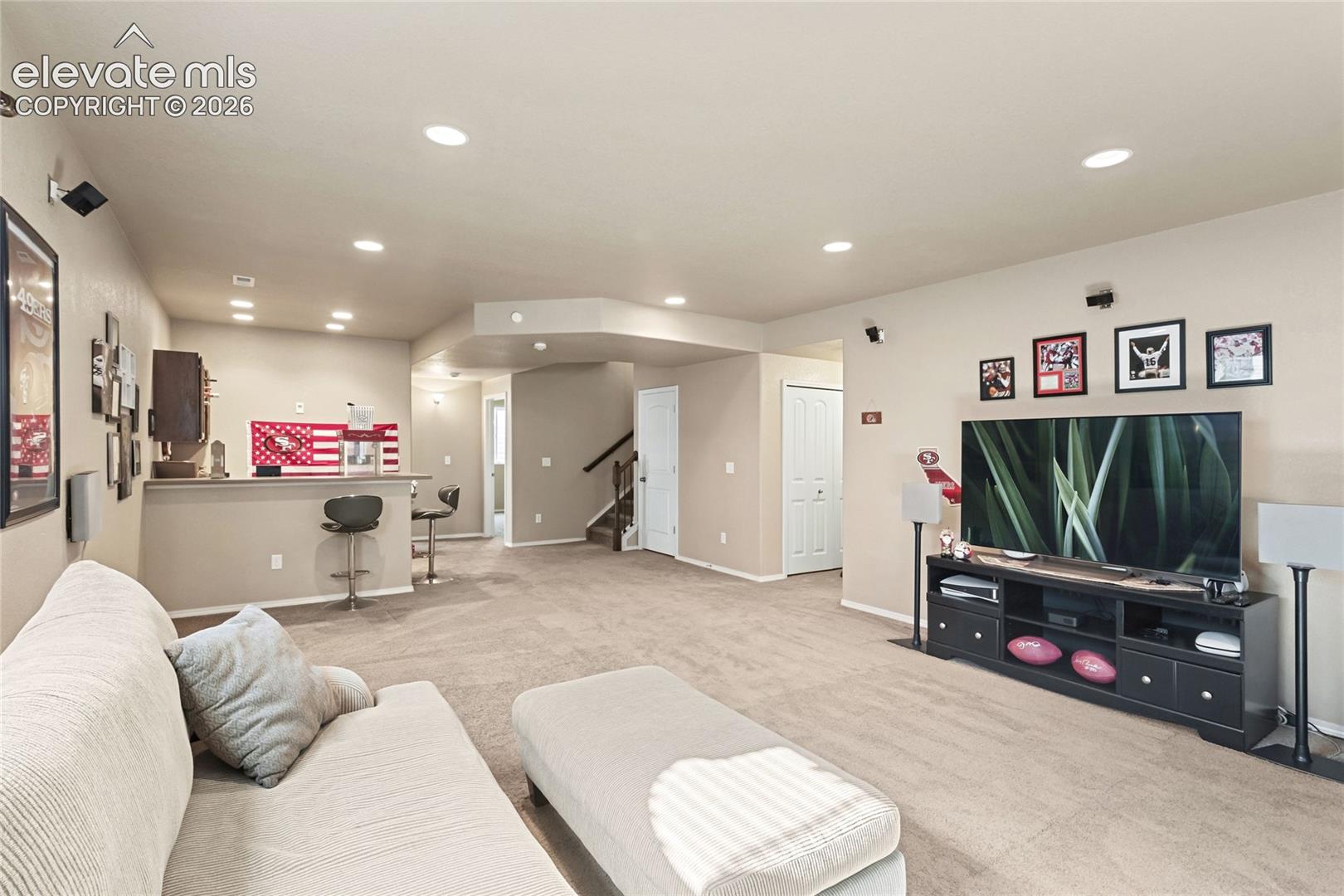 Spacious interior featuring recessed lighting, carpeted flooring, and a built-in wet bar with a raised counter