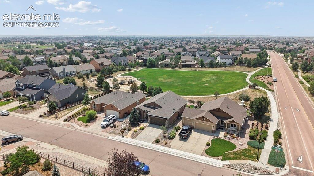 Aerial view showcasing this modern estate situated on a generous lot with manicured landscaping, multiple attached structures, and a circular driveway