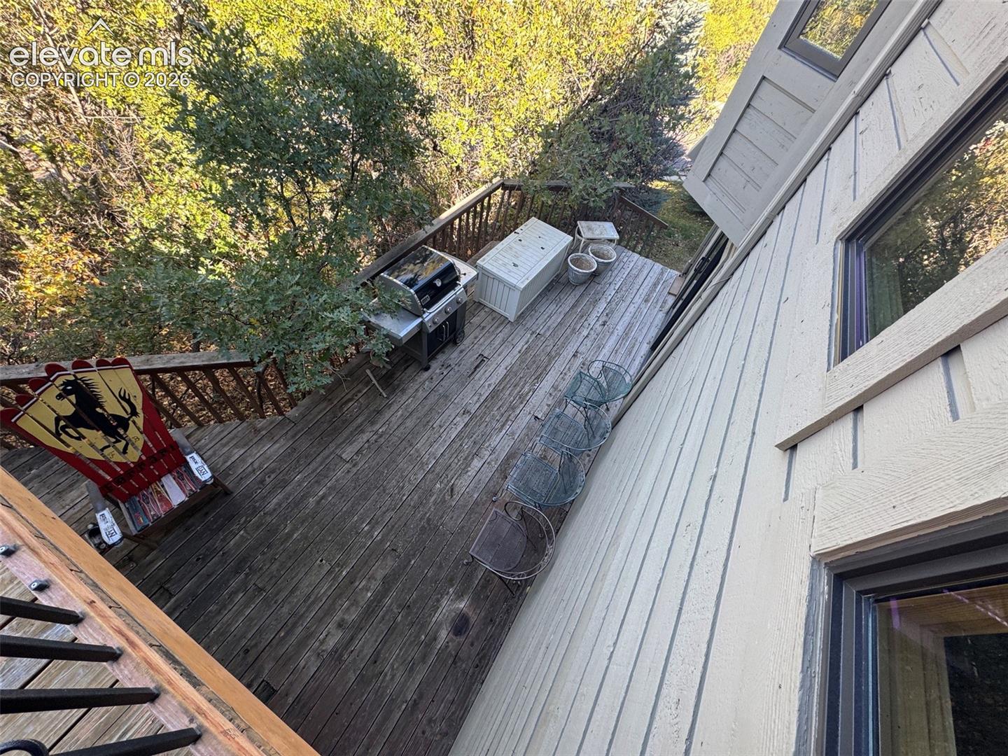 Elevated wood-plank deck featuring horizontal wood siding, integrated railing, and mature trees
