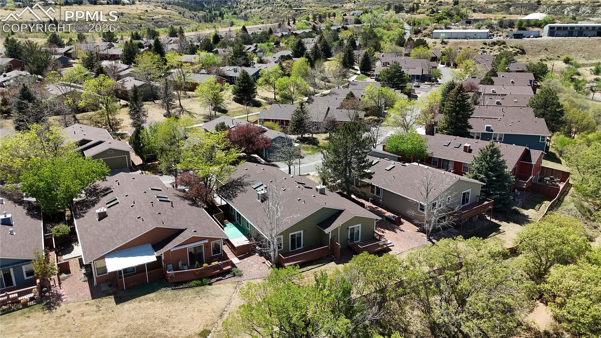 The property is situated within a residential community featuring a variety of homes with pitched roofs, surrounded by mature trees and natural landscaping