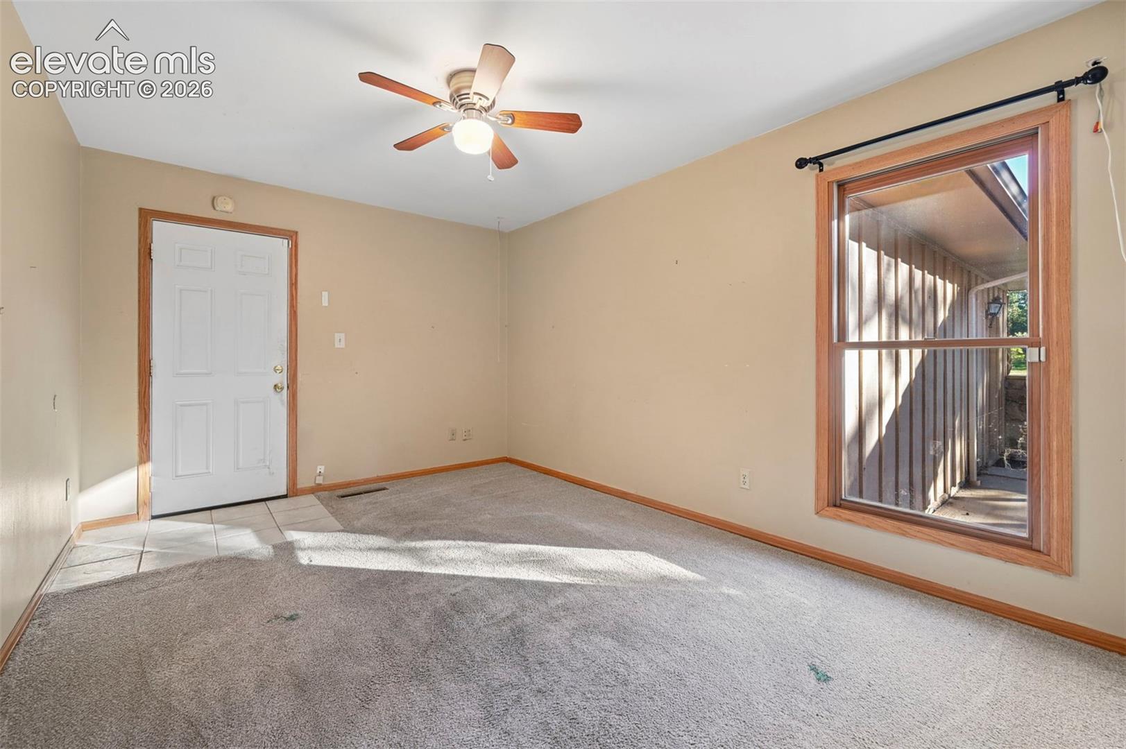 Ceiling fan with integrated lighting, wood-trim window, and tiled entry