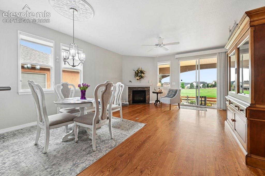 Hardwood-finish flooring, built-in fireplace with tile surround, ceiling fan, sliding glass door, and a decorative ceiling medallion with a chandelier