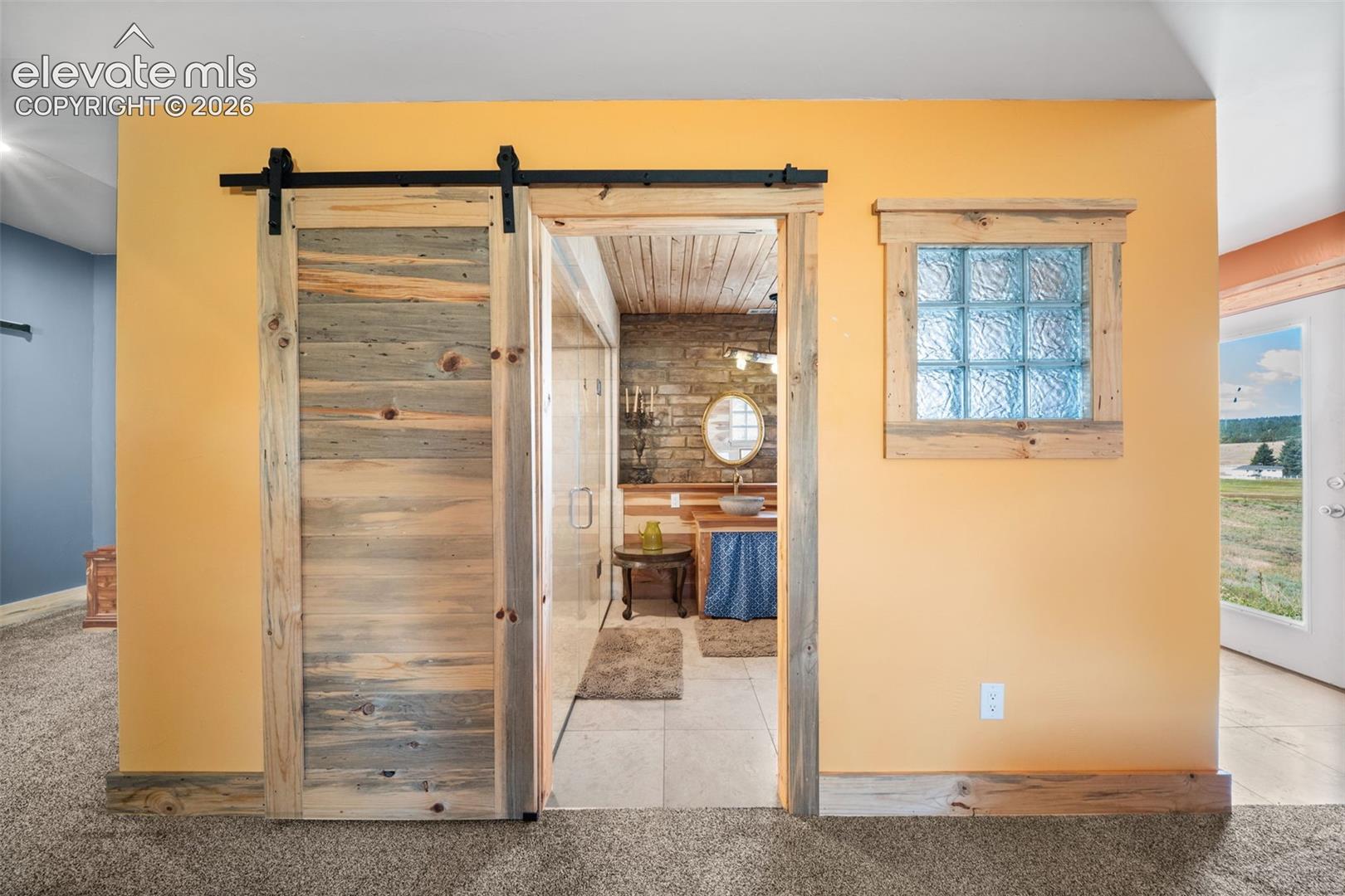 Custom Bettkill pine barn doors lead to the private primary bath.