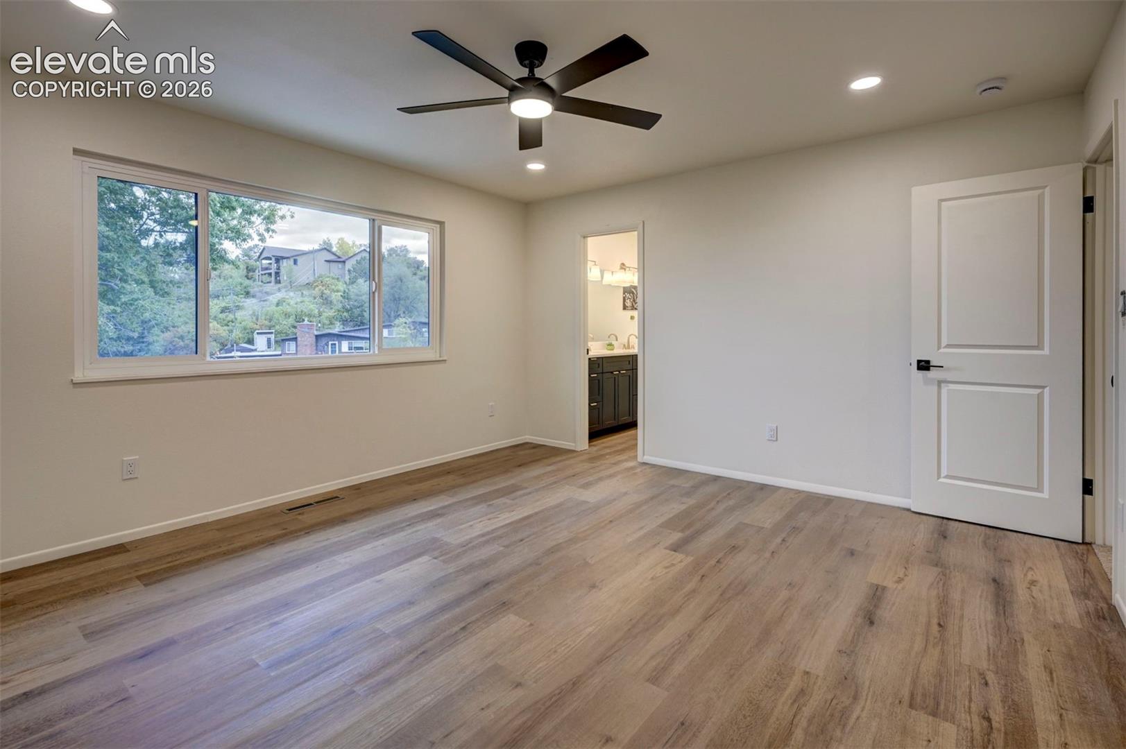 Interior room featuring wood-finish flooring, a large multi-pane window, recessed ceiling lighting, and a modern ceiling fan with a light fixture