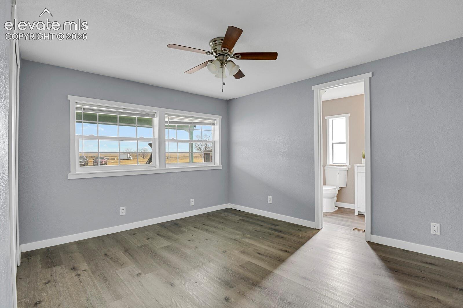 Room featuring wood-finish flooring, dual-pane windows, and a ceiling fan with integrated lighting
