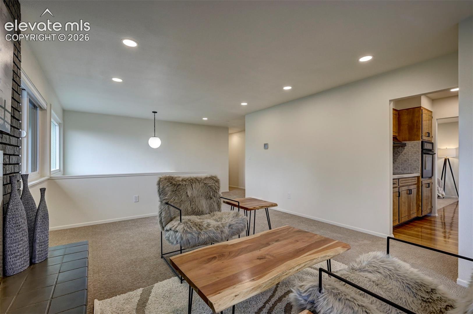 Interior space featuring recessed lighting, a stone-accented fireplace surround, and wood-finish flooring