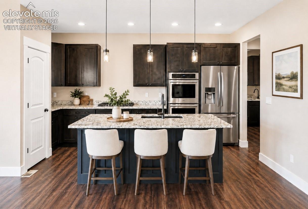 Virtually Staged Modern kitchen featuring a central island with seating, granite countertops, stainless steel appliances, dark wood cabinetry, and wood-finish flooring