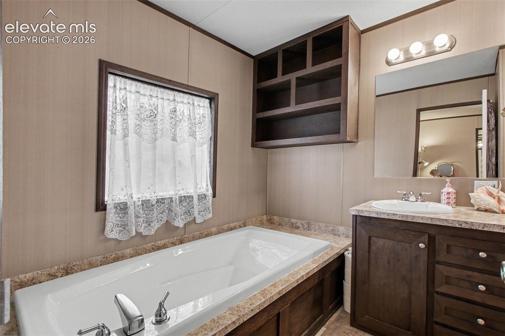 2nd Home: Primary bathroom featuring a tub with built-in shelving offering both functionality and convenience.