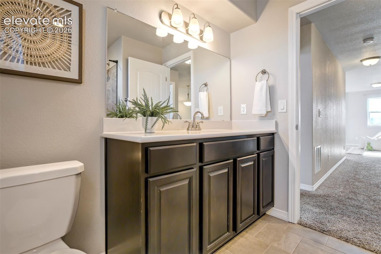 Vanity with an integrated sink, brushed nickel faucet, and a wall-mounted mirror