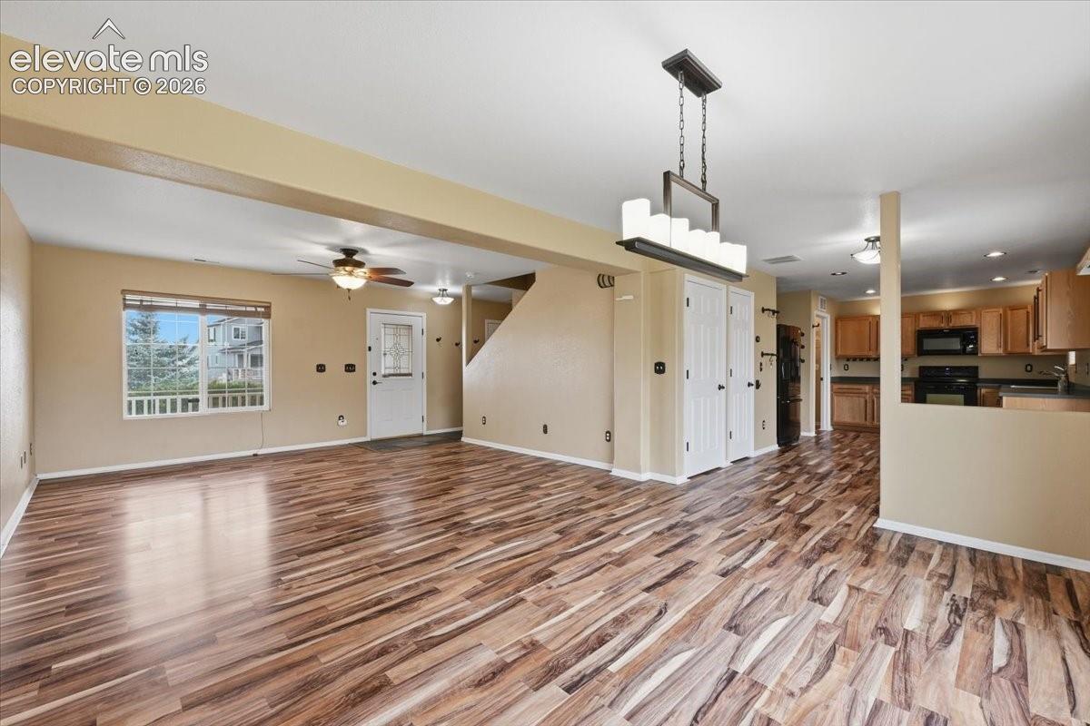 Open concept living area featuring wood-finish flooring, a modern chandelier, and a ceiling fan