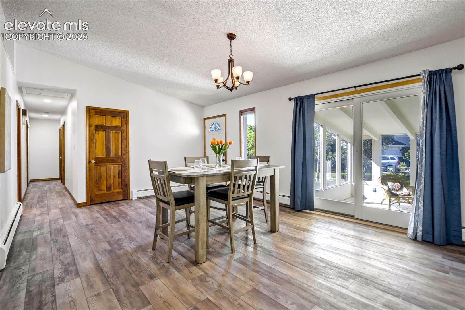 Spacious interior featuring wood-finish flooring, a contemporary chandelier, and sliding glass doors to a sunroom