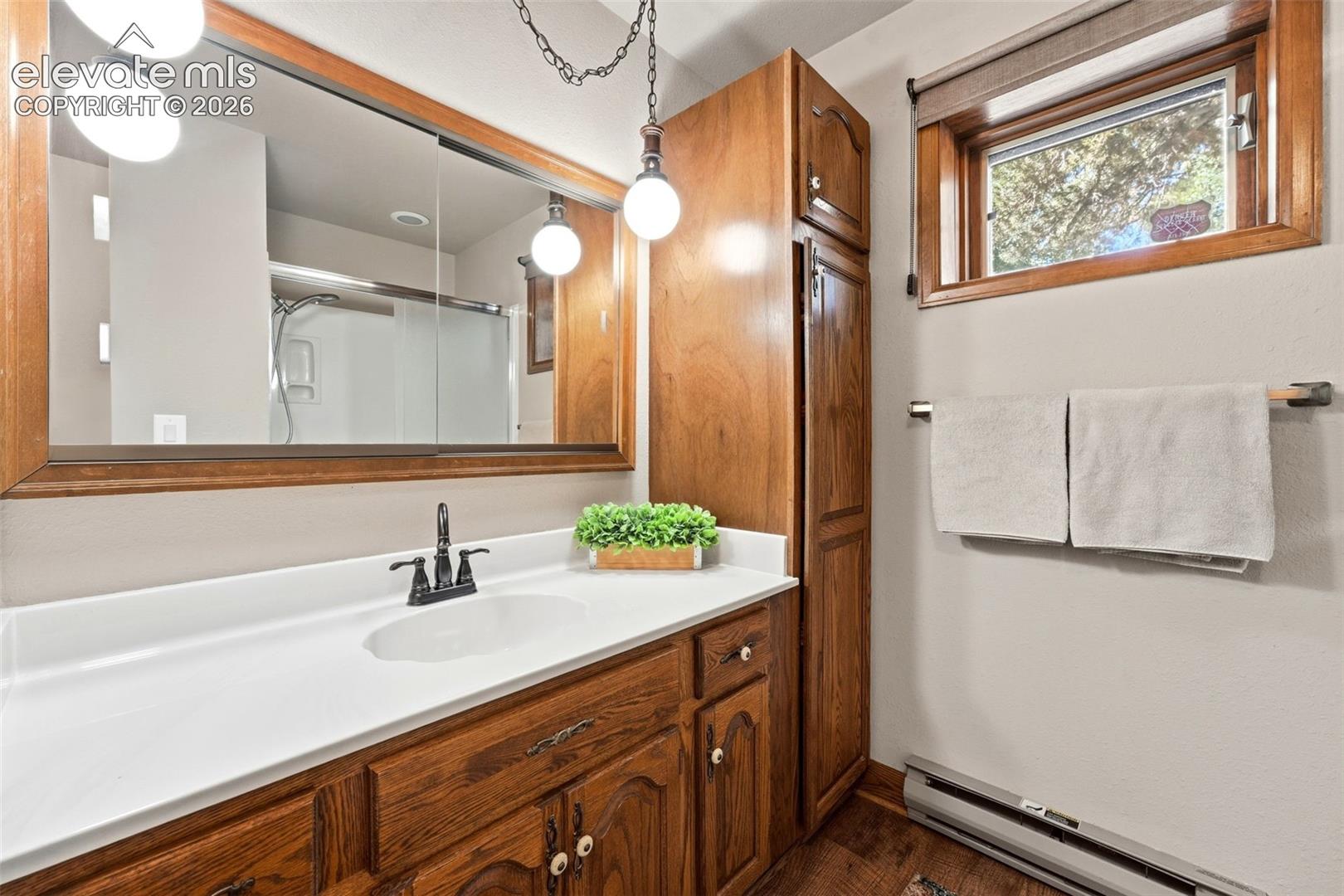 Wood-finish cabinetry and vanity with a white countertop and integrated sink