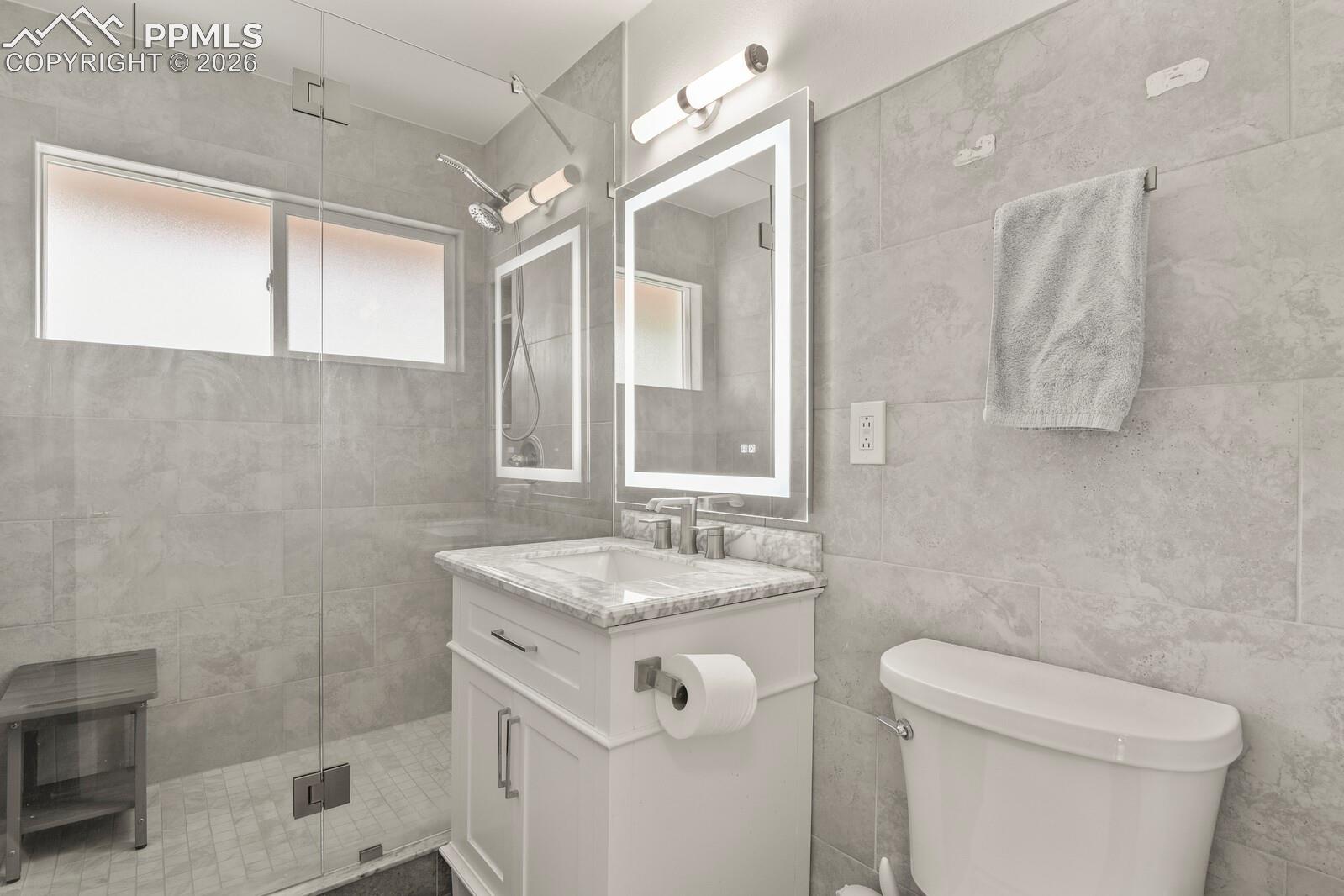 Bathroom featuring a frameless glass shower door with dual shower heads
