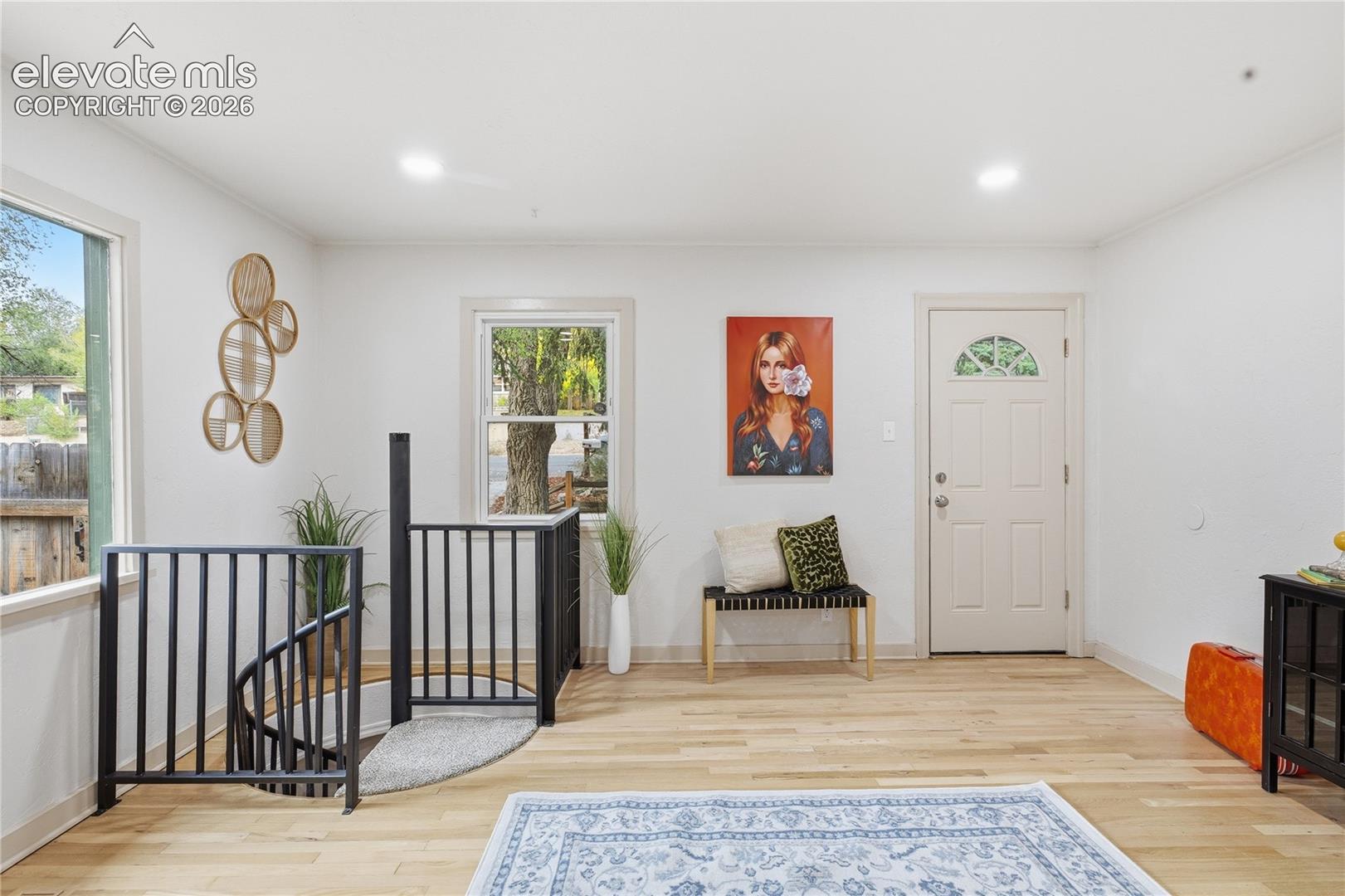 Interior area featuring light-toned wood-finish flooring, recessed lighting, and a metal spiral staircase with matching railings